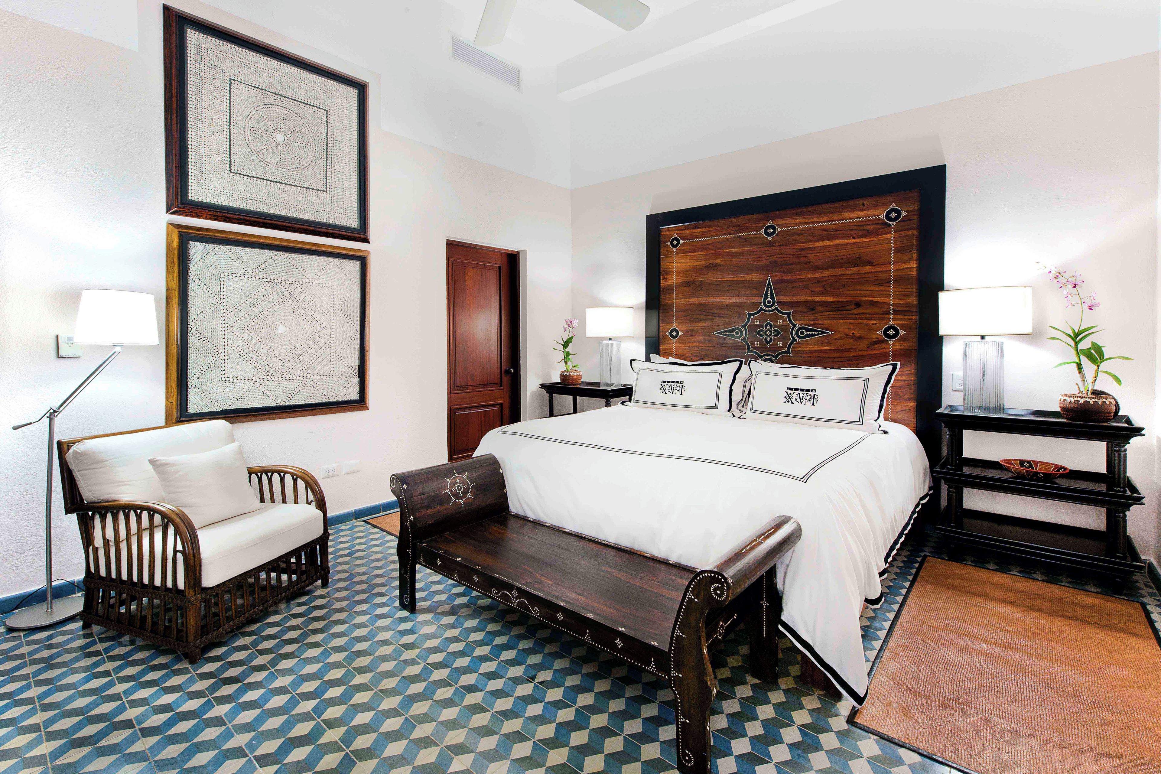 Een hotelkamer met een groot bed, een bankje, een bureau en een stoel.