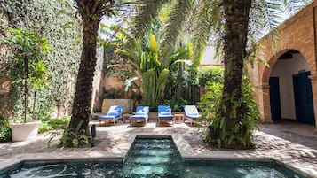 Un área de piscina con sillas de descanso y una pequeña fuente.