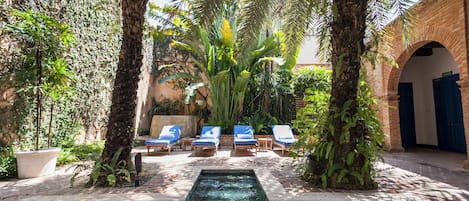 A pool area with lounge chairs and a small water feature.