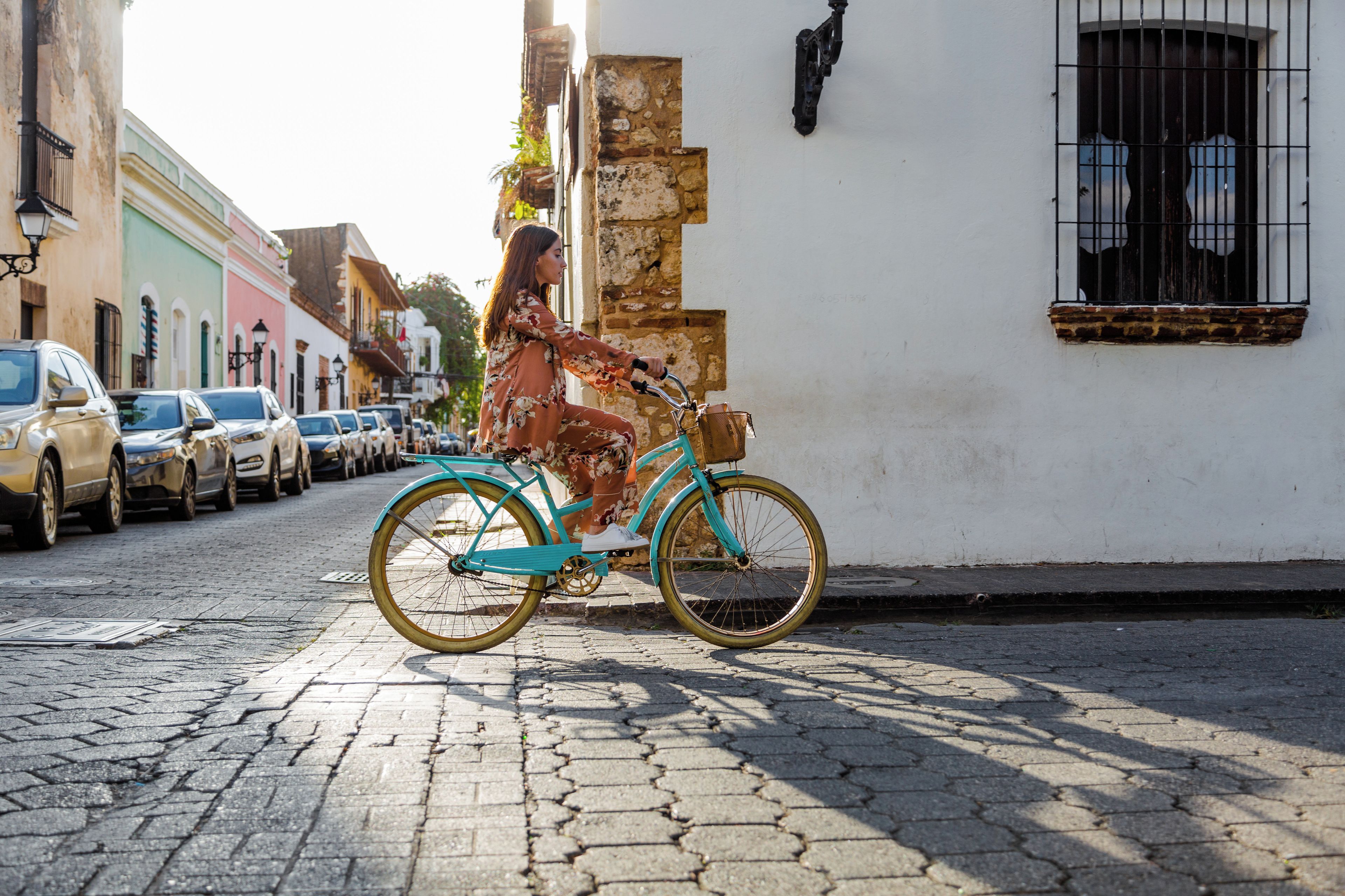 A cobblestone street with a turquoise bicycle parked against a building with a window and a door.