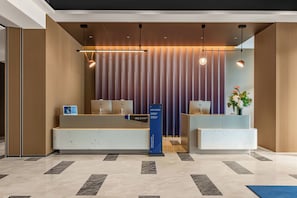 A hotel reception area with a modern design, featuring a reception desk, a digital information board, and a reception counter.