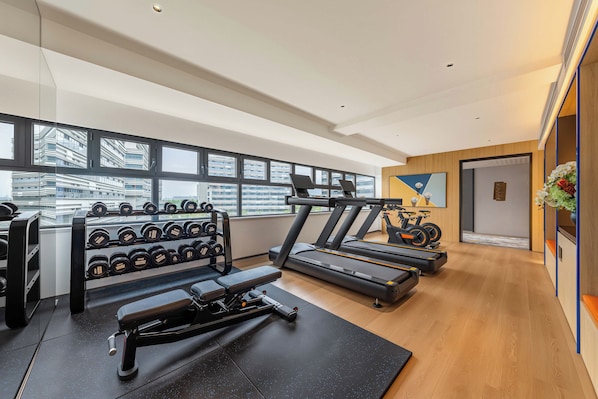 Un gimnasio moderno con cintas de correr, mancuernas y equipo de ejercicios.