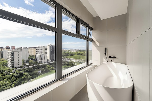A modern bathroom with a large window, a bathtub, and a view of a cityscape.