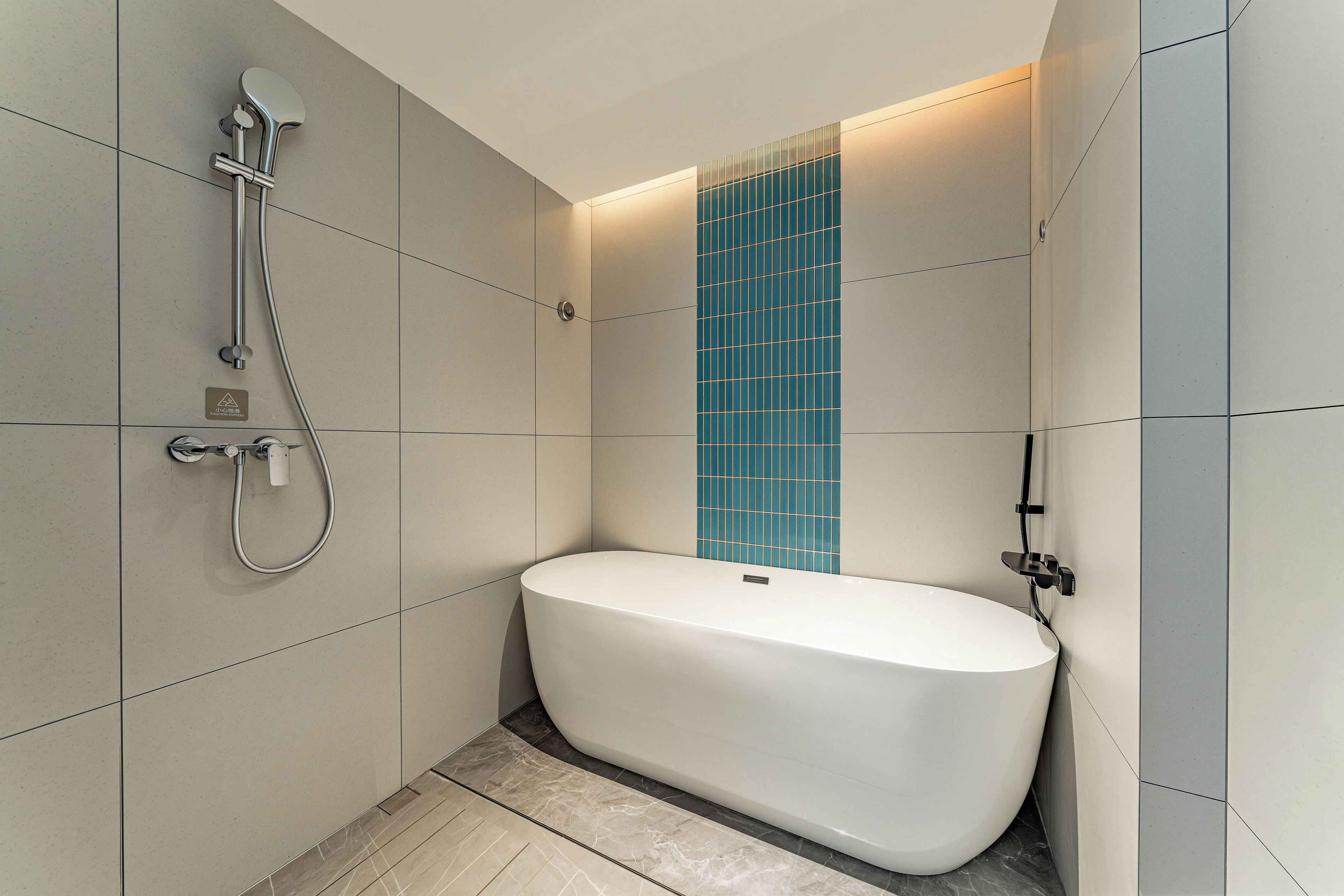 A modern bathroom with a freestanding bathtub, a shower head, and a wall-mounted control panel.