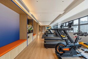 A gym with exercise equipment, wooden flooring, and large windows.