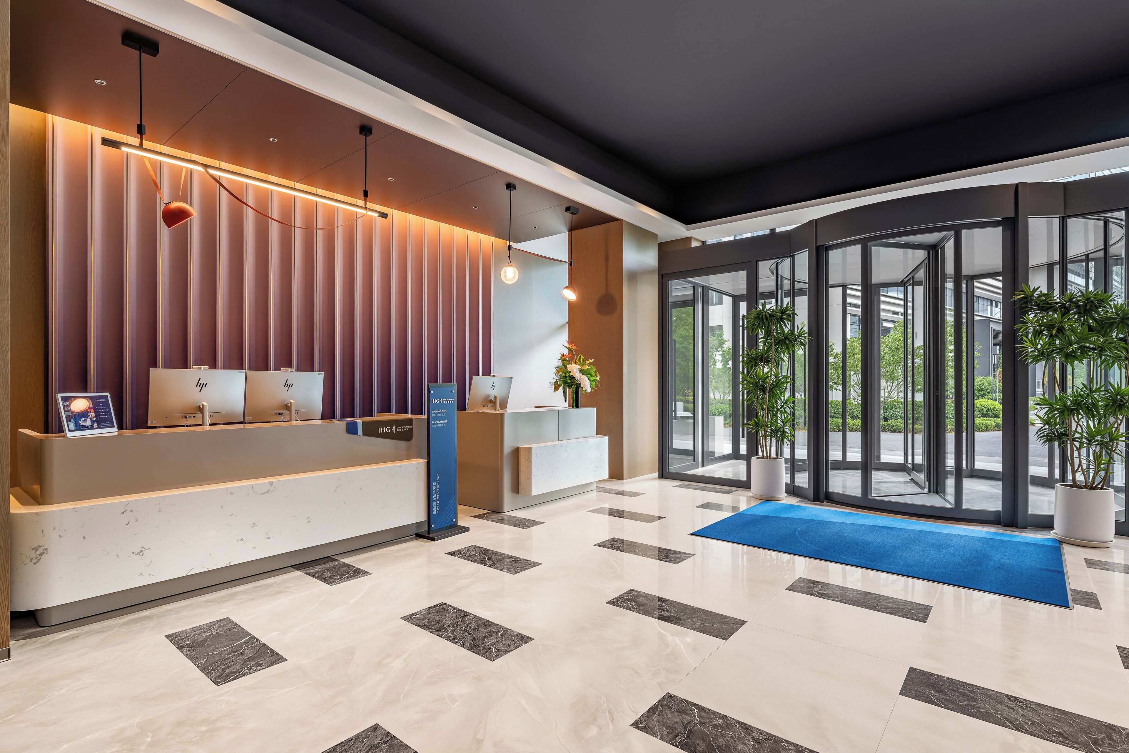 A modern reception area with a marble floor, a reception desk, and a large glass door leading outside.