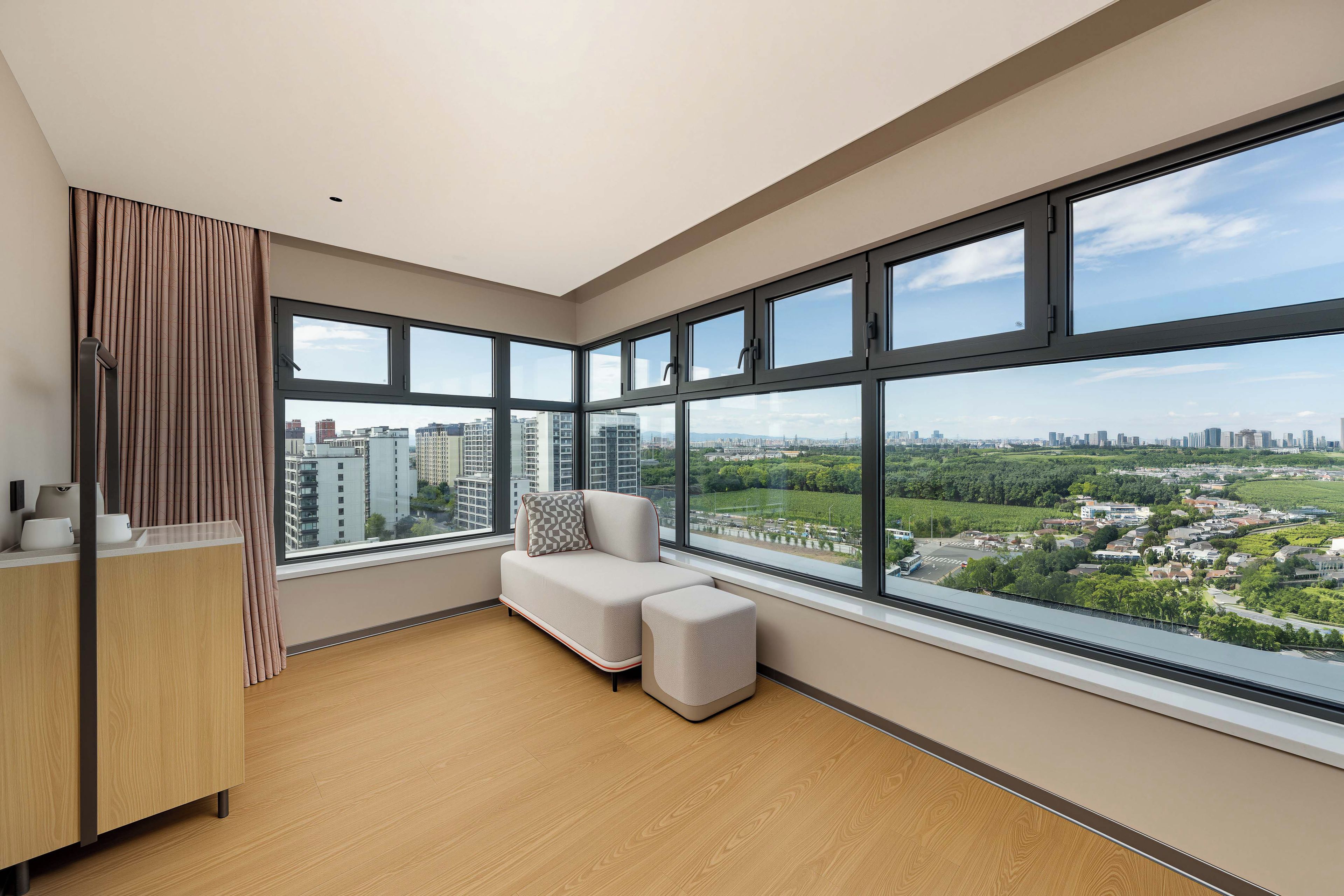 A modern apartment with large windows, a sofa, and a wooden floor.