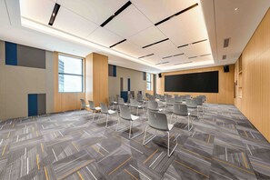 A conference room with a large screen, rows of chairs, and a patterned carpet.