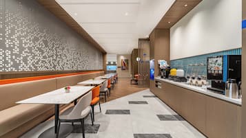 Un restaurant moderne avec de longues tables, des banquettes et un bar à café.