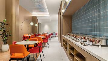 A modern dining area with round tables and chairs, a buffet line, and a decorative ceiling feature.