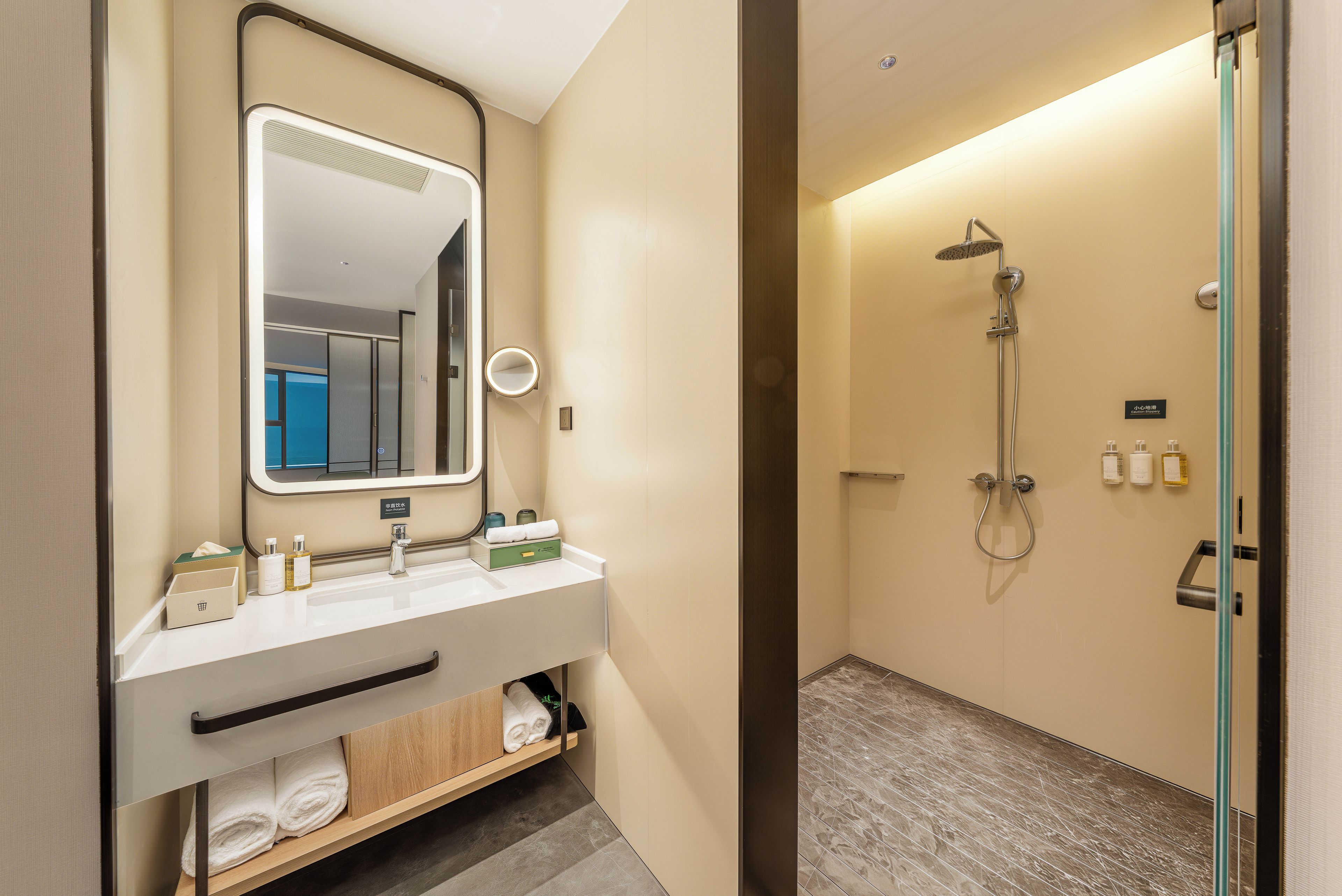 A hotel bathroom with a mirror, two sinks, a shower, and a towel rack.