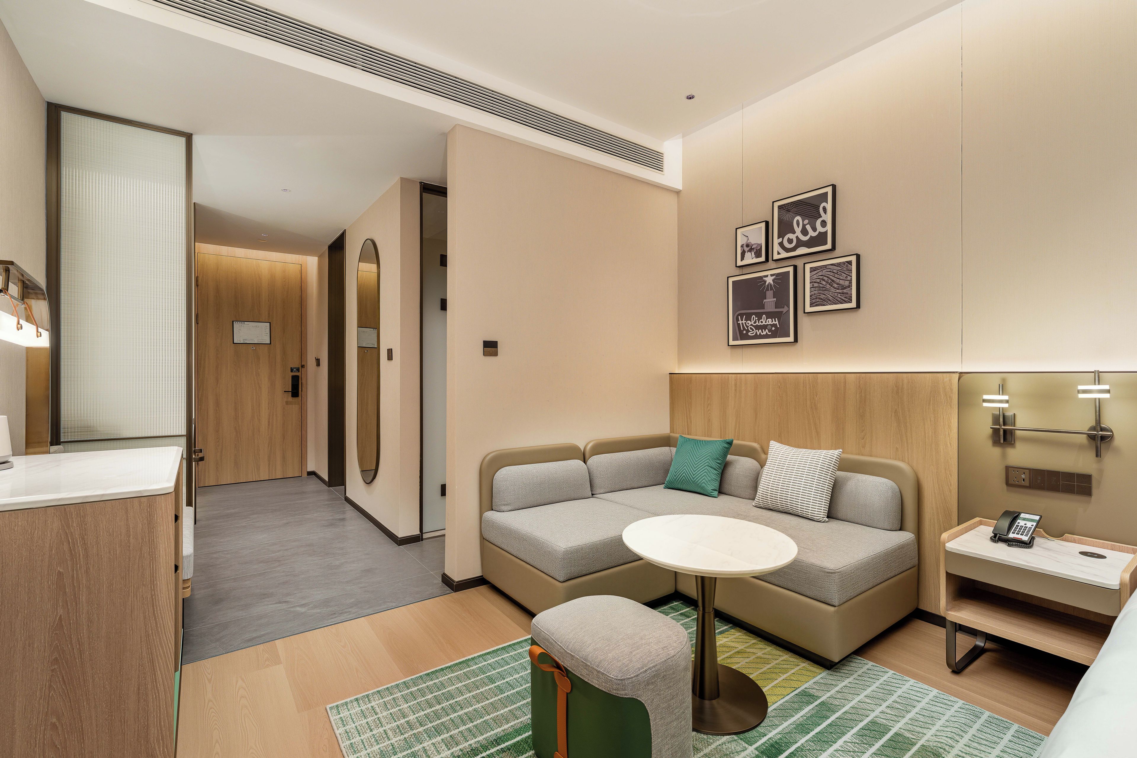 A modern hotel room with a sofa, a small table, a telephone, and a mirror.