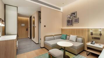 A modern hotel room with a sofa, a small table, a telephone, and a mirror.
