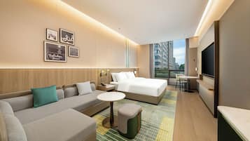 A modern hotel room with a sofa, a bed, a small table, and a TV.