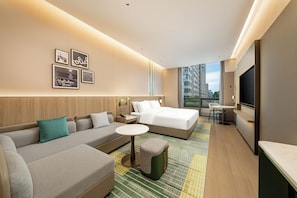 Une chambre d’hôtel moderne équipée d’un canapé, d’un lit, d’une petite table et d’un téléviseur.