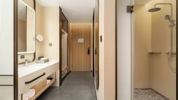 A modern bathroom with a shower, a vanity with a mirror, and a towel rack.