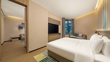 A hotel room with a large bed, a TV, a seating area, and a view of the outdoors.