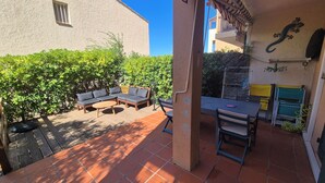 Een terras met tuinmeubilair, een tafel en een stoel.