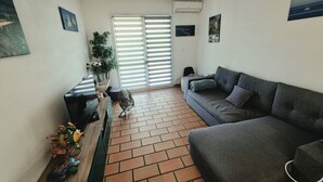 A living room with a grey sofa, a wooden coffee table, and a potted plant.