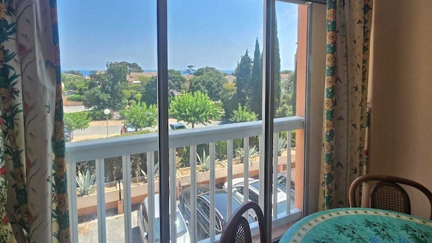 Un balcon donnant sur un parking et sur des espaces verts.
