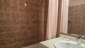 Une salle de bain avec une baignoire, un lavabo avec deux verres et un miroir.