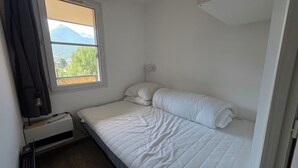En säng för en person med vita sängkläder i ett rum med ett fönster.