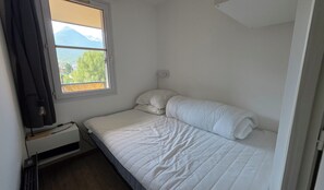 A single bed with white bedding in a room with a window. - Apartment "Le Col de Mélodies" with balcony (Briançon)