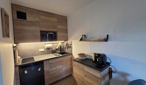 Eine kleine Küche mit integriertem Mikrowellenherd, einer Kaffeemaschine und einem Spülbecken.