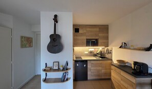 Eine moderne Küche mit Holzschränken, einer eingebauten Mikrowelle und einer Kaffeemaschine.
