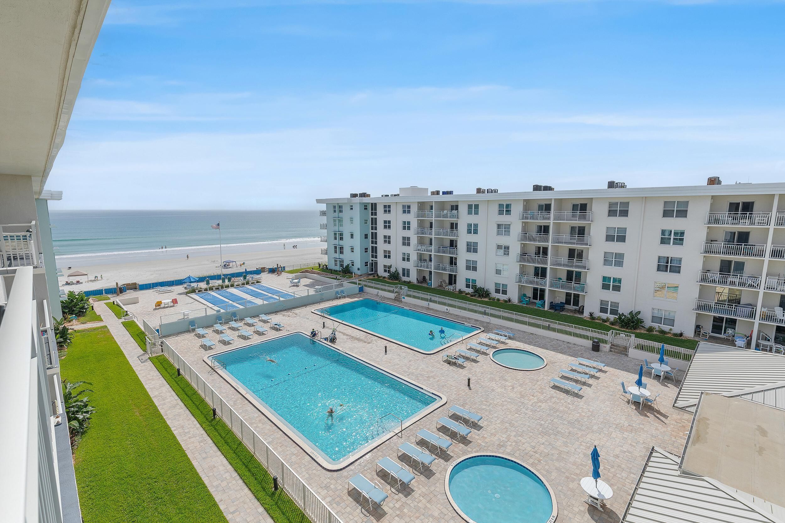 A hotel with multiple swimming pools, a beach, and a view of the ocean.