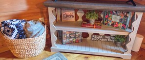 Ein Holzhütten-Tisch mit einem gewebten Korb, ein Buch mit dem Titel 'National Parks' und ein Schild mit der Aufschrift 'RELAX... WE'RE ON CABIN TIME'.
