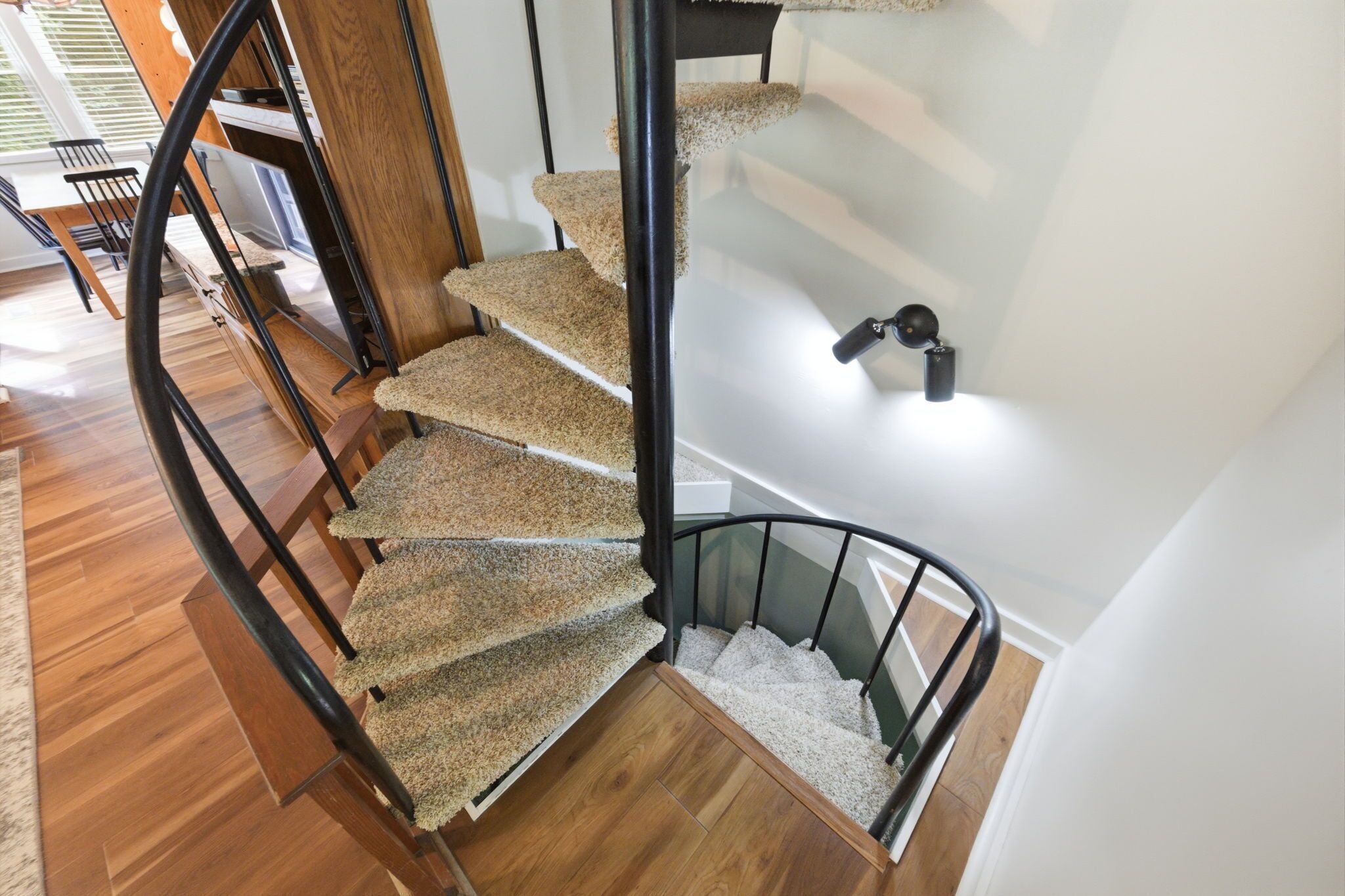 A spiral staircase with carpeted steps and metal railings.