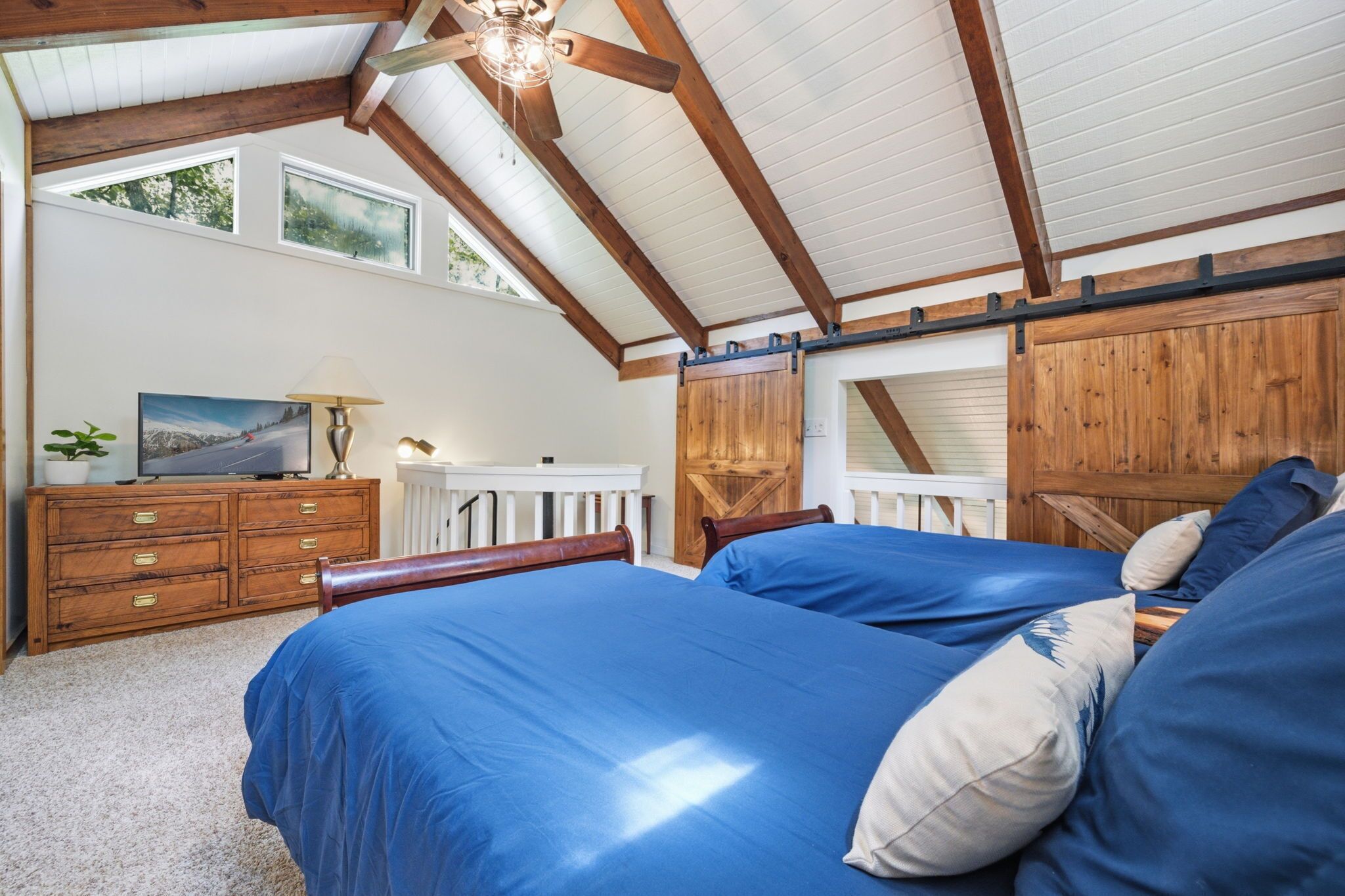 Une chambre avec un grand lit, une commode, un téléviseur et un mur en bois de style grange.