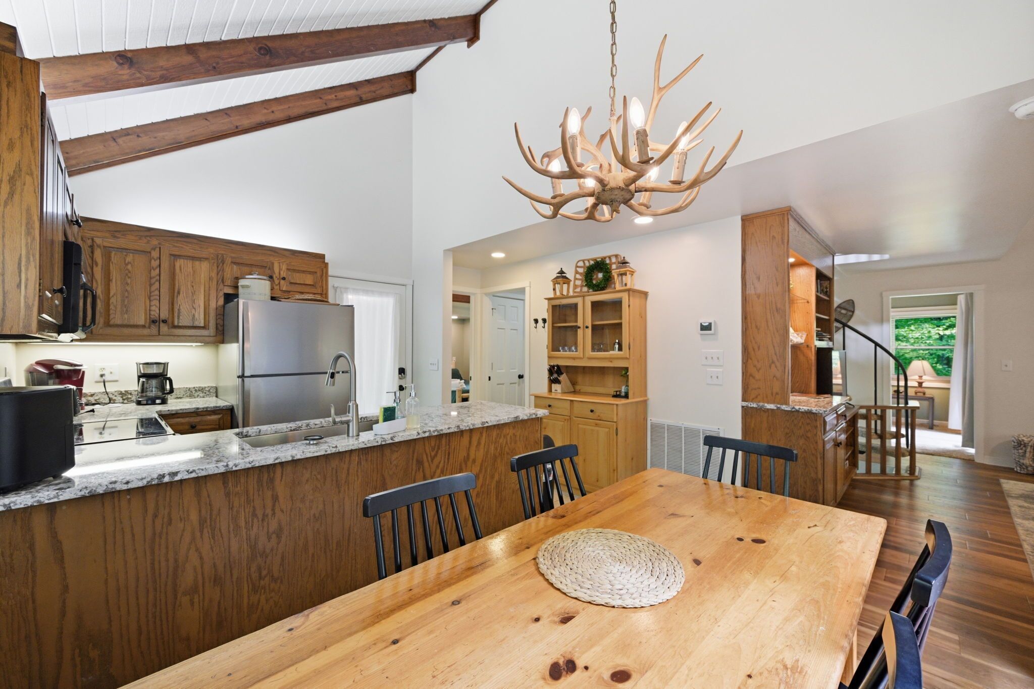 A modern kitchen with a central island, wooden cabinets, and a chandelier.