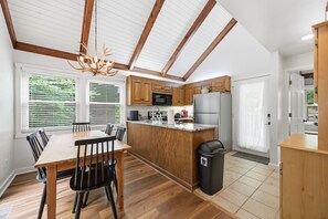 A modern kitchen with wooden cabinets, a dining table, and chairs. - Updated 3 BR Chalet/Walk to Sugar Mountain Resort/ Hot tub/ Fireplace (Sugar Mountain)
