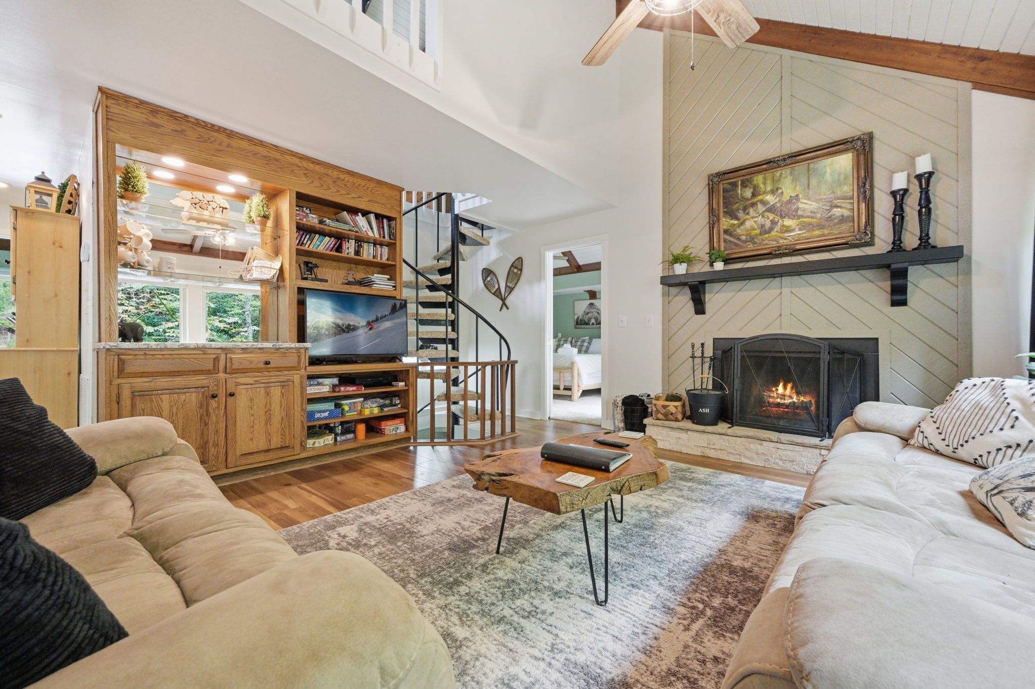 A spacious living room with a fireplace, a wooden staircase, and a cozy seating area.
