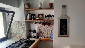 A kitchen with a gas stove, shelves with kitchenware, a kettle, and a chalkboard with a message. - Apartment 'Civico 5' with Wi-Fi and Air Conditioning (Lamezia Terme)