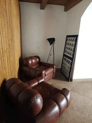 Une pièce avec un canapé en cuir marron, un lampadaire et un tableau encadré accroché au mur.