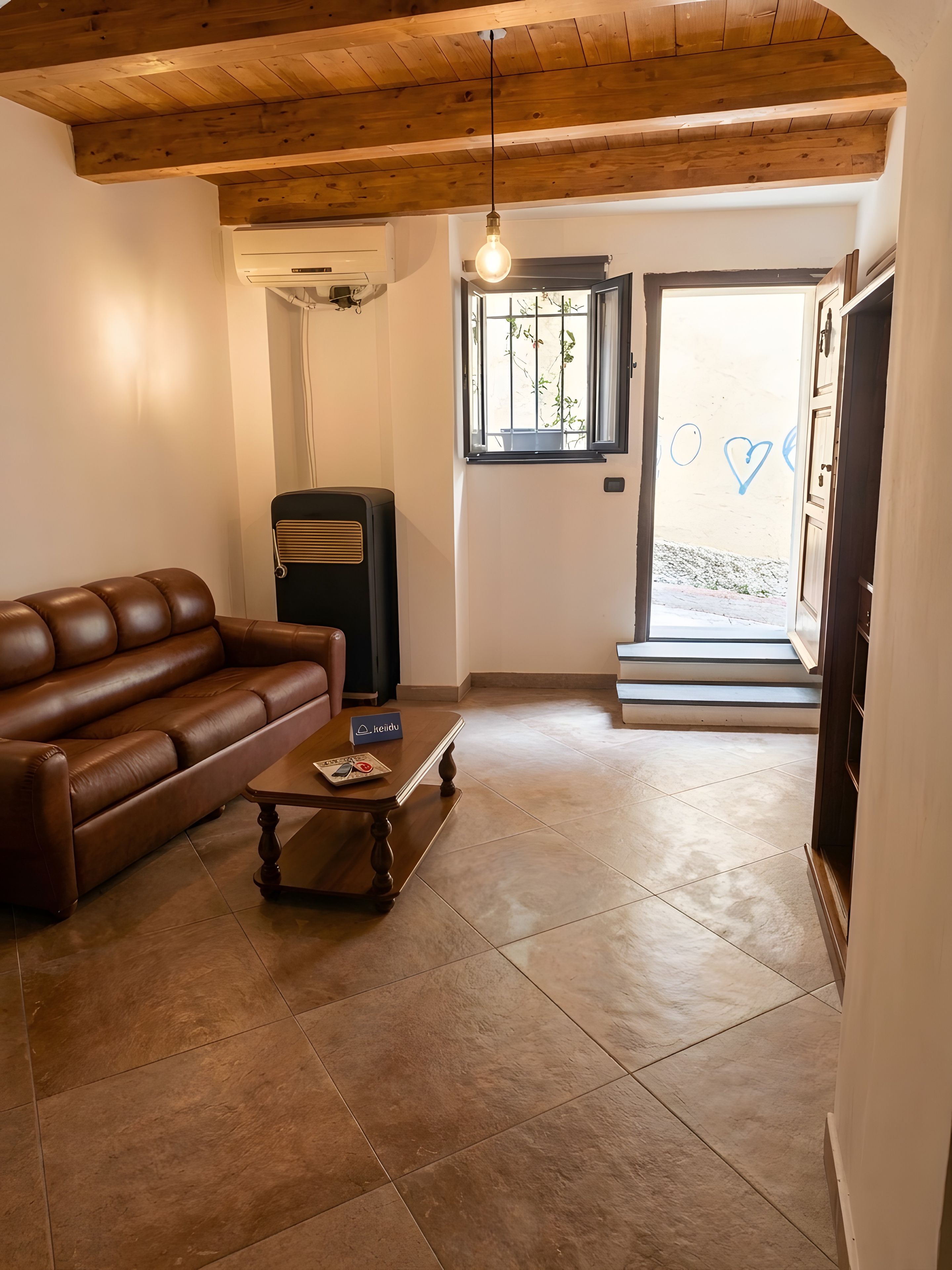 A living room with a brown leather sofa, a wooden coffee table, and a black heater.