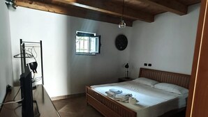 A bedroom with a wooden ceiling, a bed, a desk, a window, and a wall clock. - Apartment 'Civico 5' with Wi-Fi and Air Conditioning (Lamezia Terme)