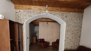 A living room with a stone wall, wooden ceiling, and a fireplace. There is a sofa, a coffee table, and a cabinet. - Apartment 'Civico 5' with Wi-Fi and Air Conditioning (Lamezia Terme)