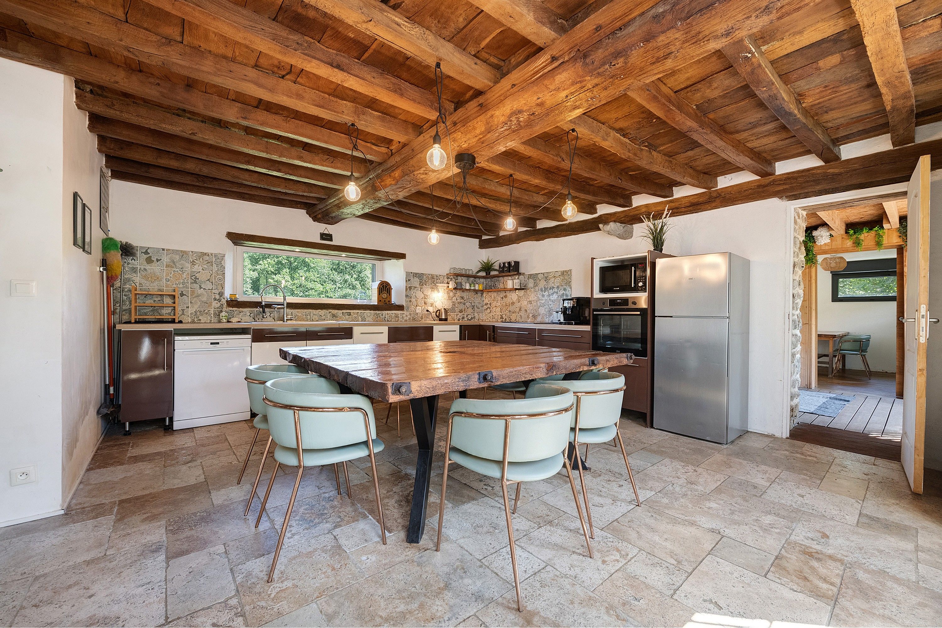 Une cuisine rustique avec une grande table en bois, quatre chaises et un four encastré.