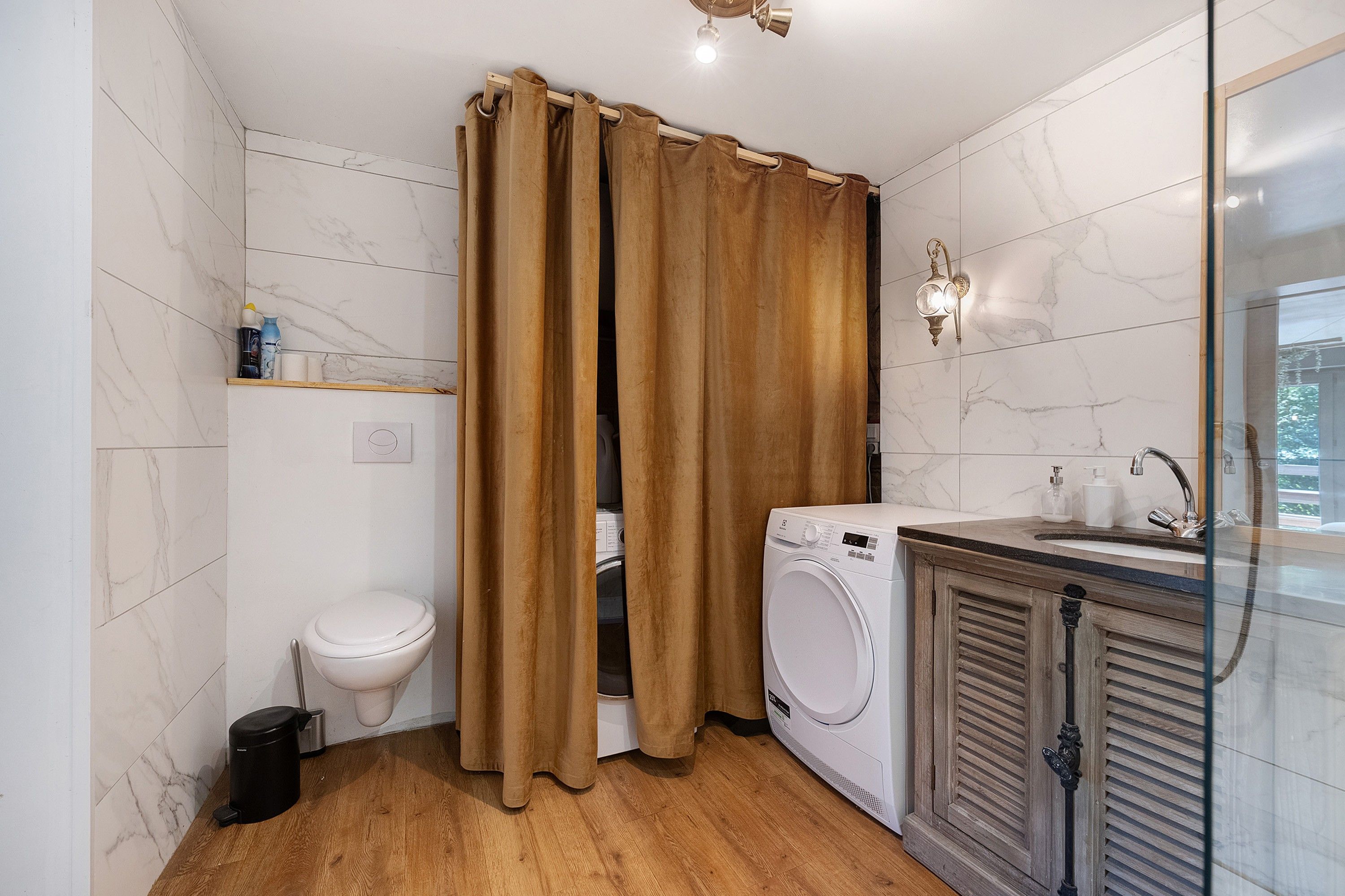 A bathroom with a toilet, washing machine, and a shower curtain.