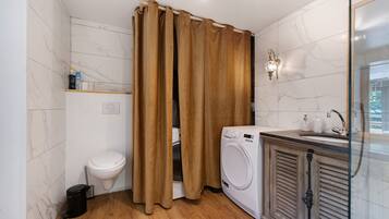 A bathroom with a toilet, washing machine, and a shower curtain.