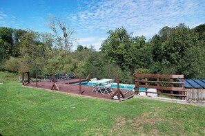 A fenced backyard with a swimming pool, outdoor seating, and a wooden deck.