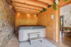 Une salle de spa avec un mur en bois, un jacuzzi, un petit banc et un plancher en bois.