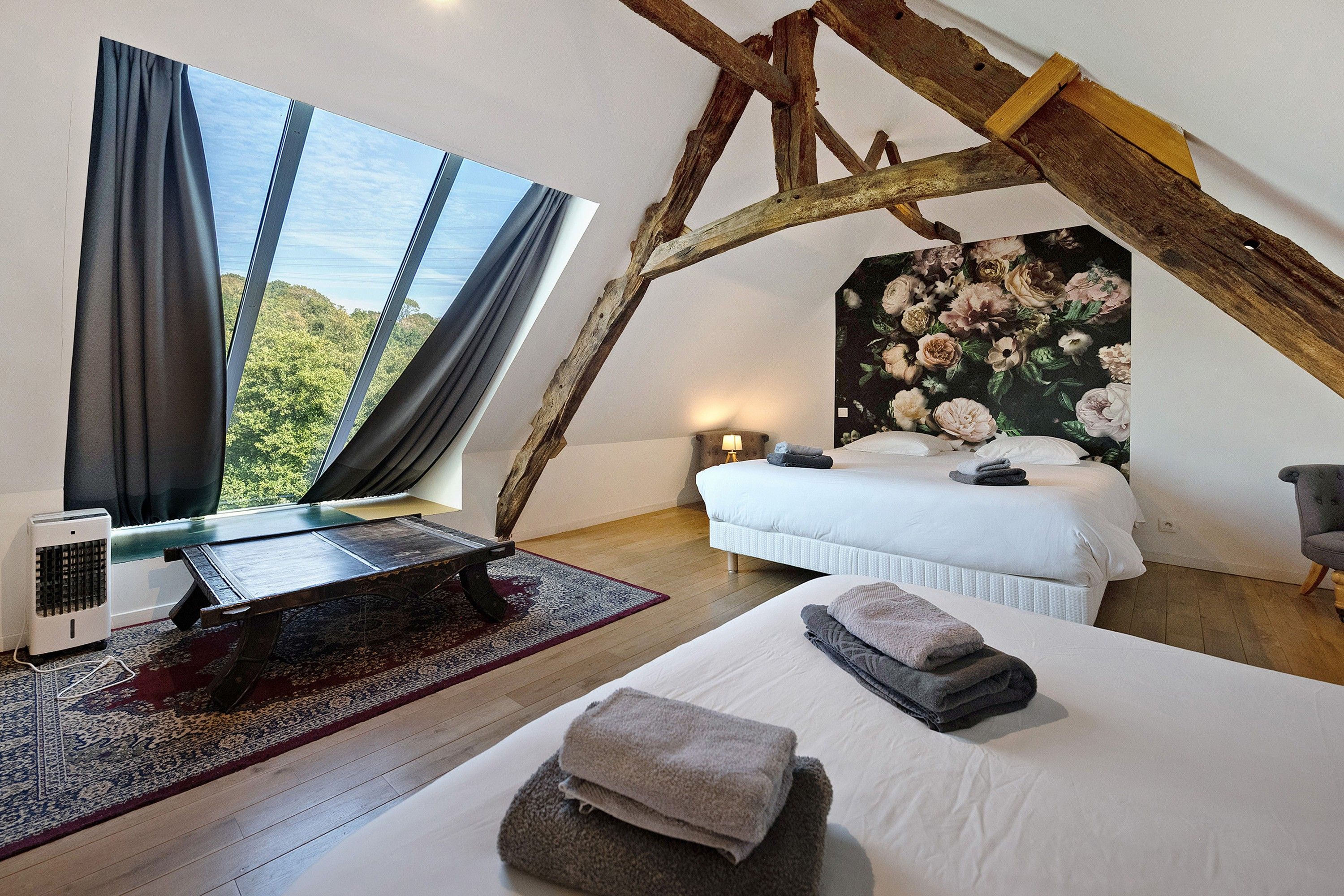 Een slaapkamer met een groot bed, een bureau, een stoel en uitzicht op het landschap.