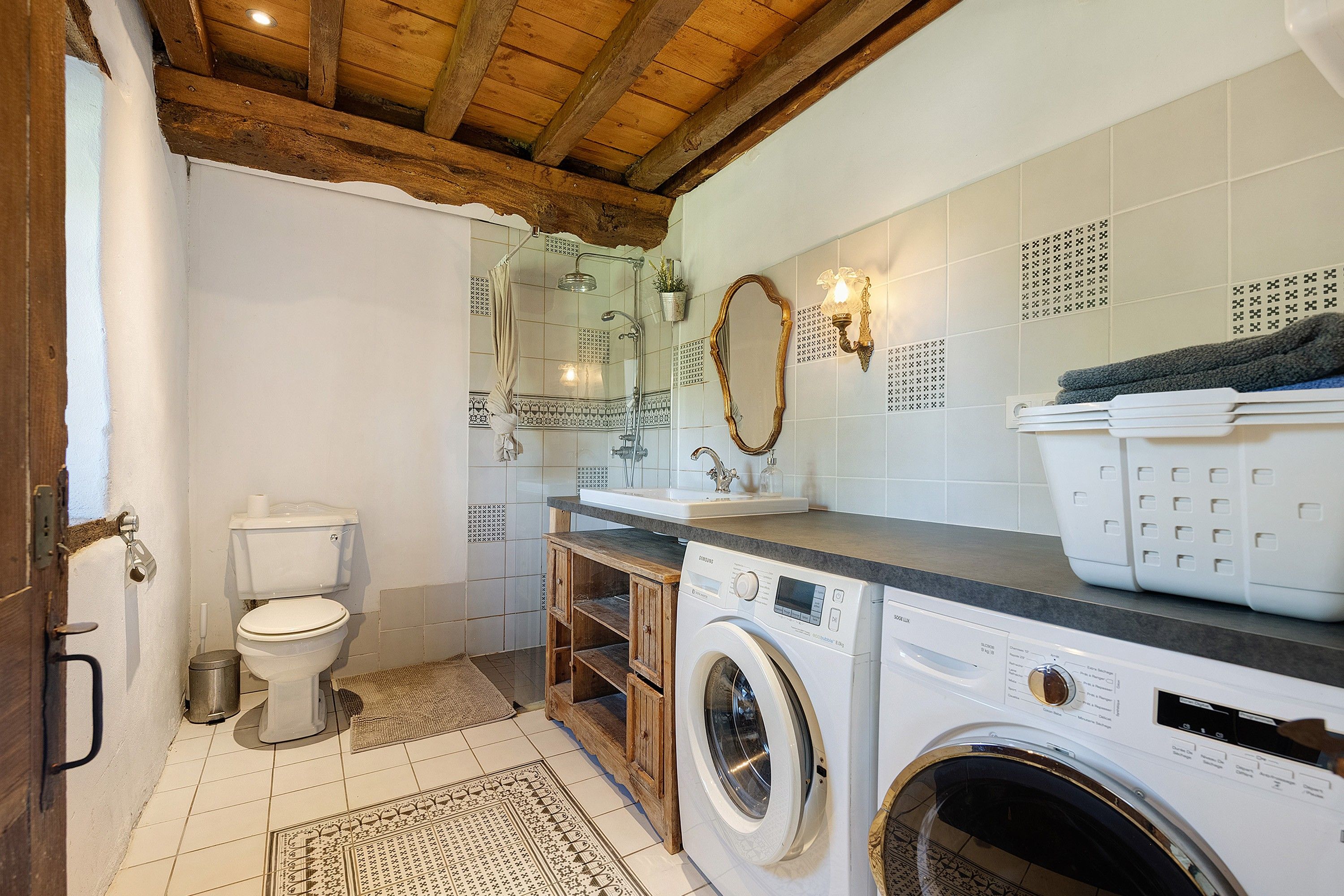 A compact bathroom with a toilet, washing machine, and sink.