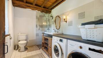 A compact bathroom with a toilet, washing machine, and sink.