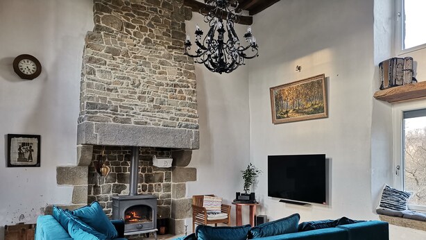Un salon chaleureux avec une cheminée en pierre, un grand téléviseur à écran plat et un canapé de couleur turquoise.